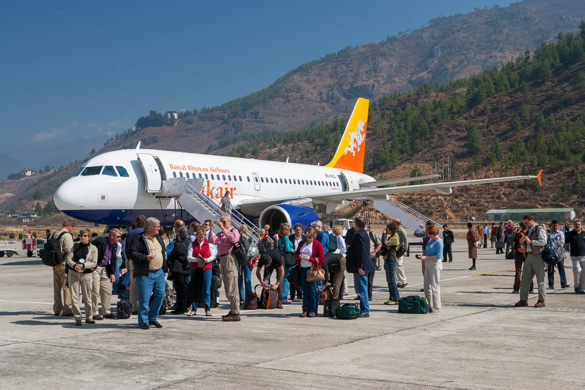 Tourists standing on the tarmac at Paro airport amazed by the scenery.